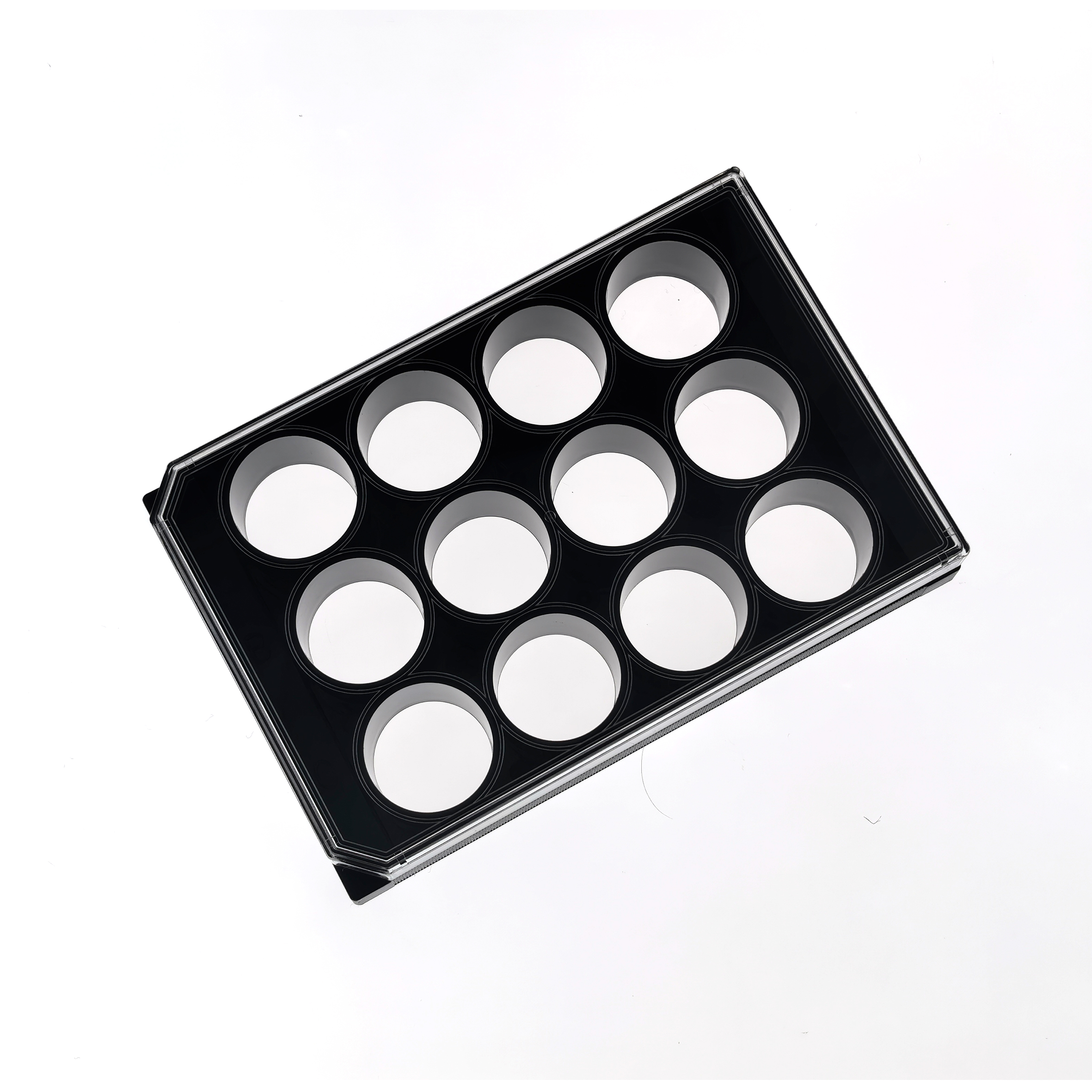 12 Well glass bottom plate (2) Black metal muffin pan with multiple round cavities photographed at a diagonal on a white background, showing glossy nonstick surfaces.